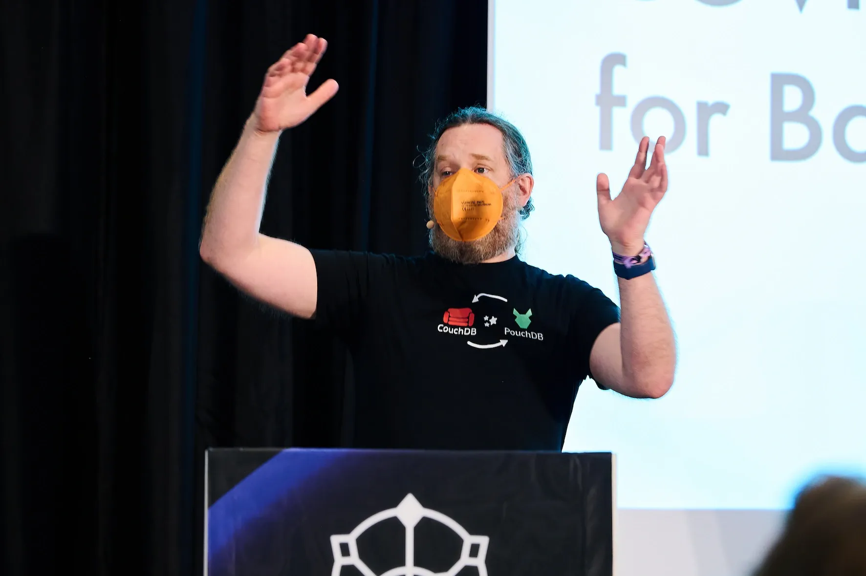 In this close up of Jan on stage, we can see him engaging directly with the audience, gesturing to convey meaning and wearing a CouchDB and PouchDB t-shirt. Photo by Susanne ElsÀsser.
